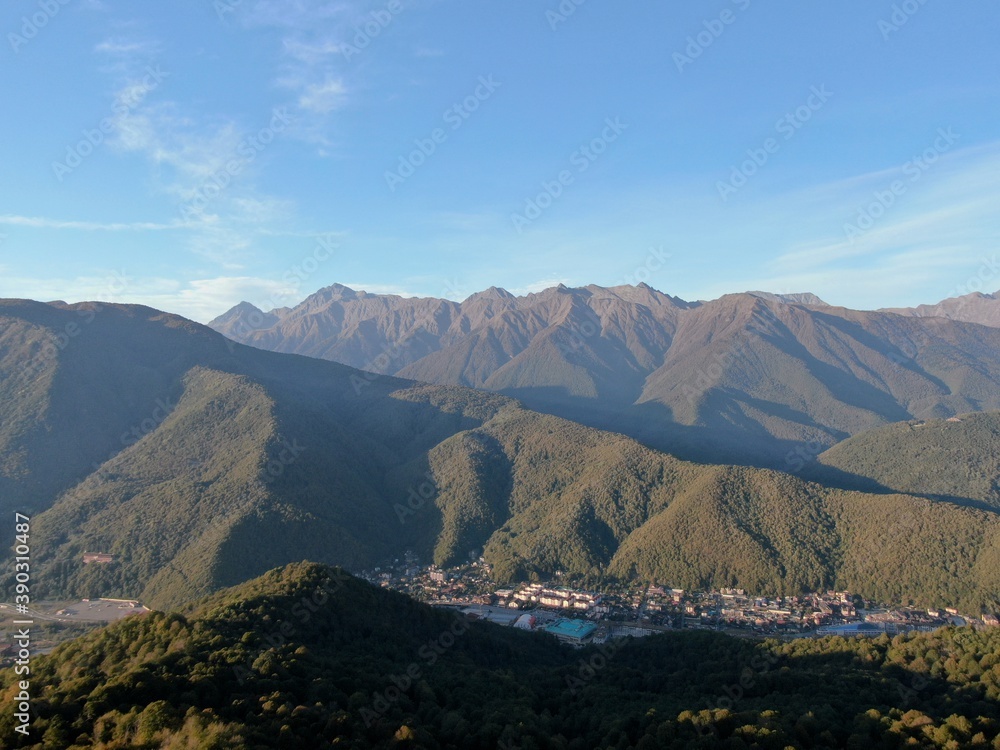 Aerial view panorama of sunset between mountains against the background of a blue sky. Beautiful sunset landscape in the mountains