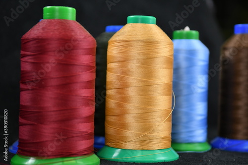 Set of colored threads for sewing on coils. Pile of big colorful spools of thread. Colored thread spools of thread large class, textiles, background
