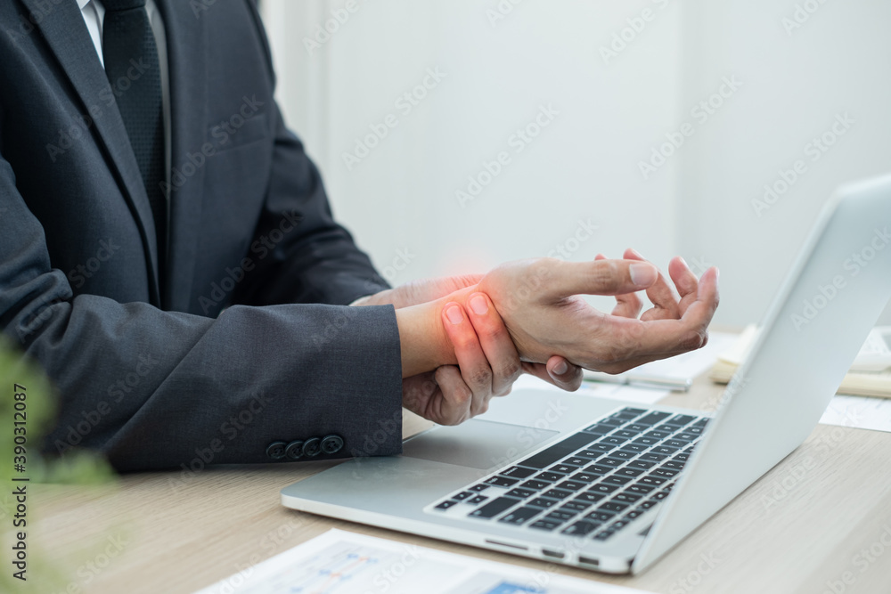 Businessman grasping the painful wrist caused by prolonged work on a laptop keyboard. Wrist numbness Arthritis While working at the office Businessman grasping the painful wrist caused by prolonged work on a laptop keyboard. Wrist numbness Arthritis While working at the office