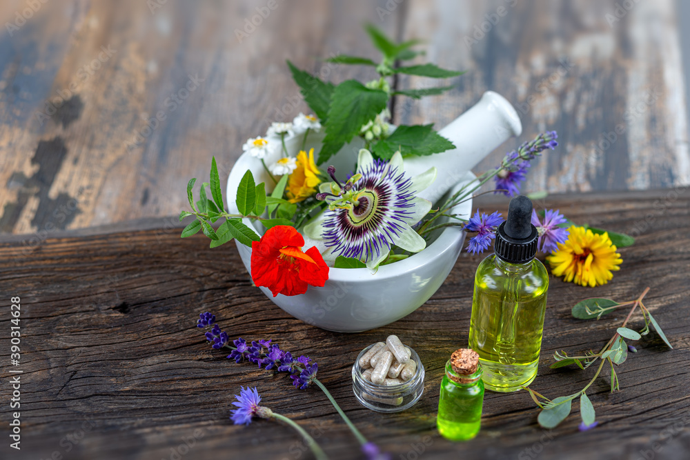 Herbs in mortar with pestle and organic essential aroma oil in glass bottle isolated on rustic background. Herbal medicine concept. Herbs in mortar with pestle and organic essential aroma oil in glass bottle isolated on rustic background. Herbal medicine concept.