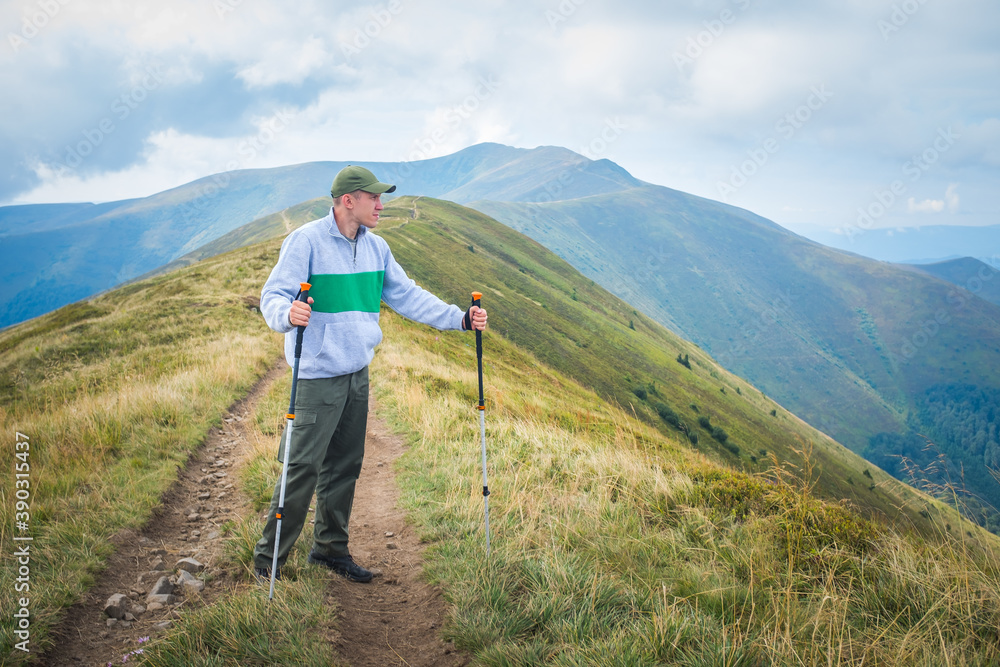Hiker Man on Hiking Trail. Summer mountains landscape. Travel and journey concept.
