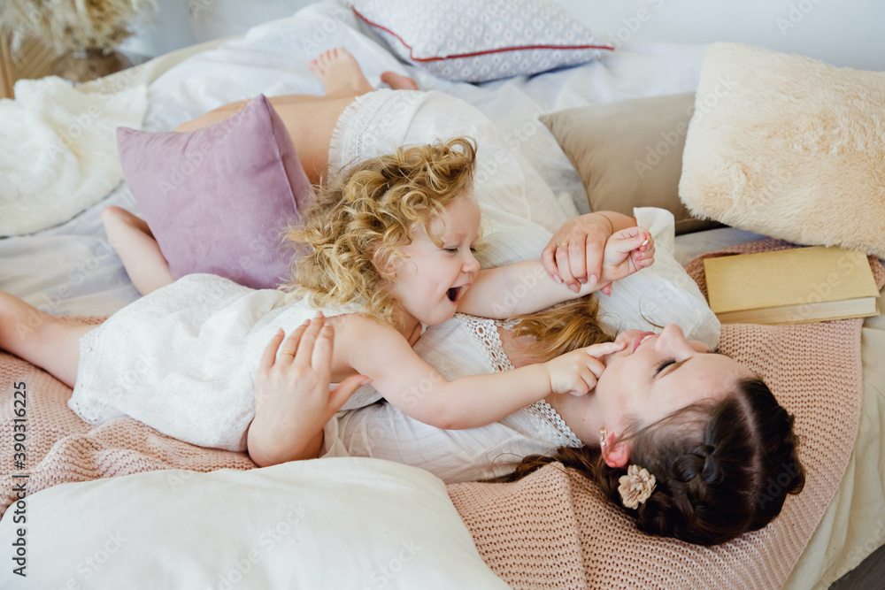 Happy loving family. Mother and daughter play and hug. The morning together. Happy games in the bedroom. Happy loving family. Mother and daughter play and hug. The morning together. Happy games in the bedroom.