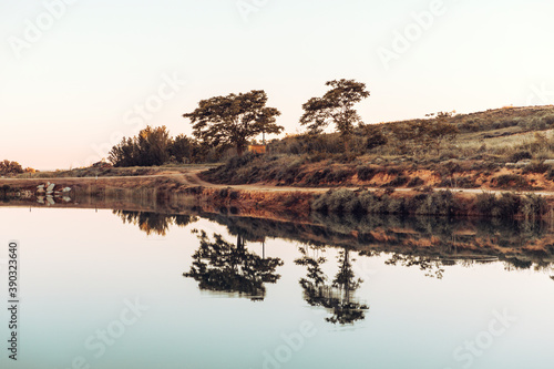 Scenic view of calm swamp and trees against clear sky during sunset. Reflection. © aitor