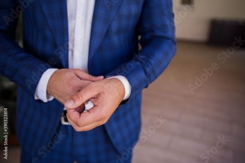 a man in a suit buttoning the cuffs of his shirt