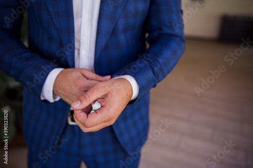 a man in a suit buttoning the cuffs of his shirt
