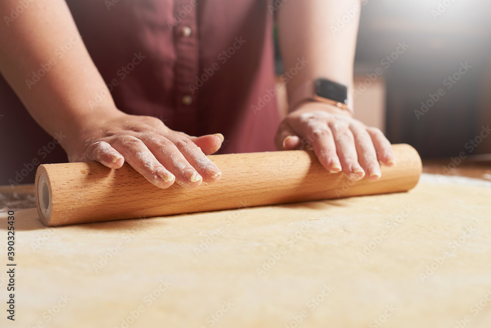 Female hands roll out the raw dough with a rolling pin Female hands roll out the raw dough with a rolling pin