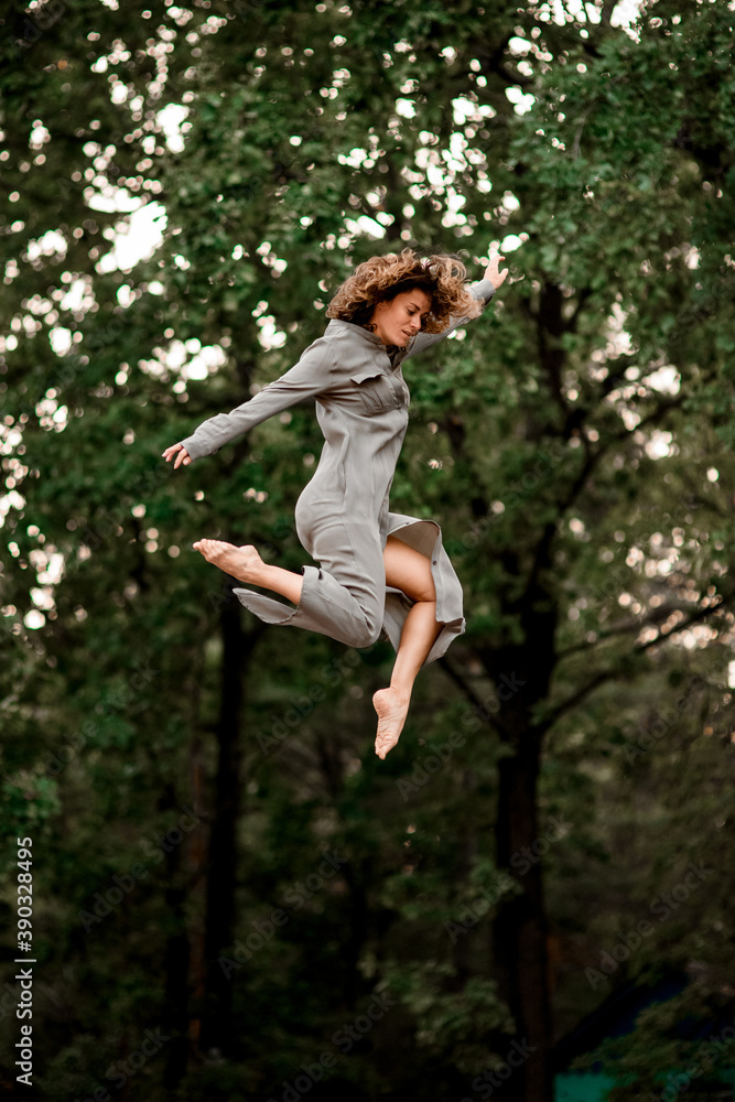 active young woman with bend knees jumps high in the air