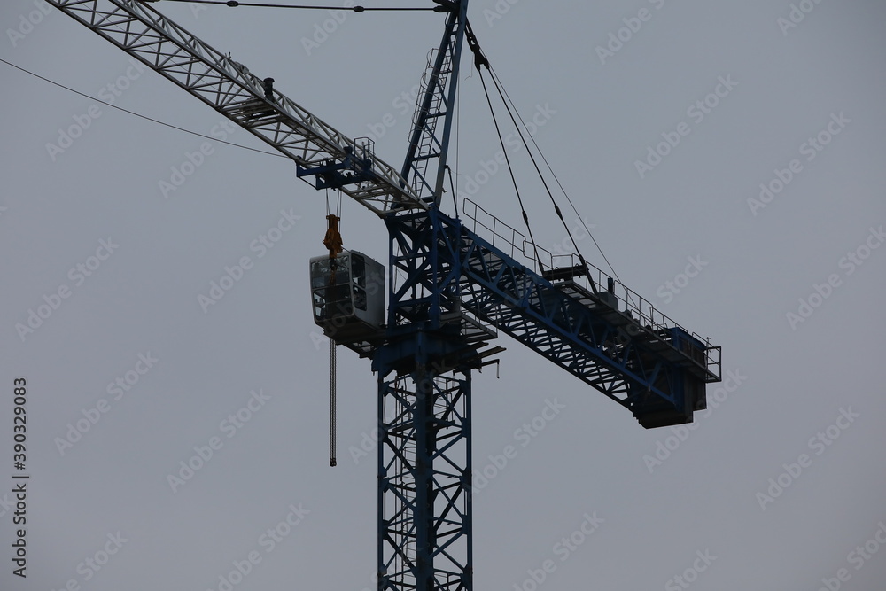 Construction crane.Cab and boom with mechanism in front of grey sky.Evening background image Construction crane.Cab and boom with mechanism in front of grey sky.Evening background image