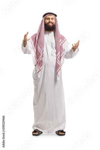 Full length portrait of a saudi arab man in a traditional thobe smiling and greeting with hands