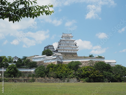 Ancient samurai castle in Himeji city in Japan with white walls  dark tile roofs and stone walls on a sunny day in summer with blue sky and white clouds