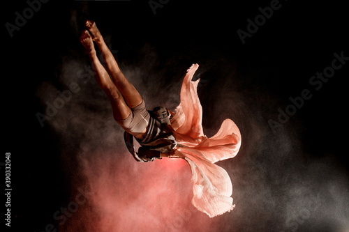 view of woman masterfully jumps and performs trick upside down in the air at dark
