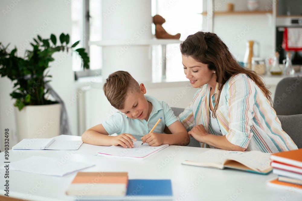 Mother helping her son with homework at home. Little boy learning at home.. Mother helping her son with homework at home. Little boy learning at home..