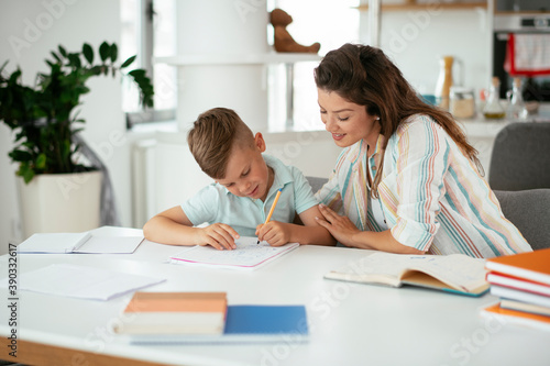 Mother helping her son with homework at home. Little boy learning at home..