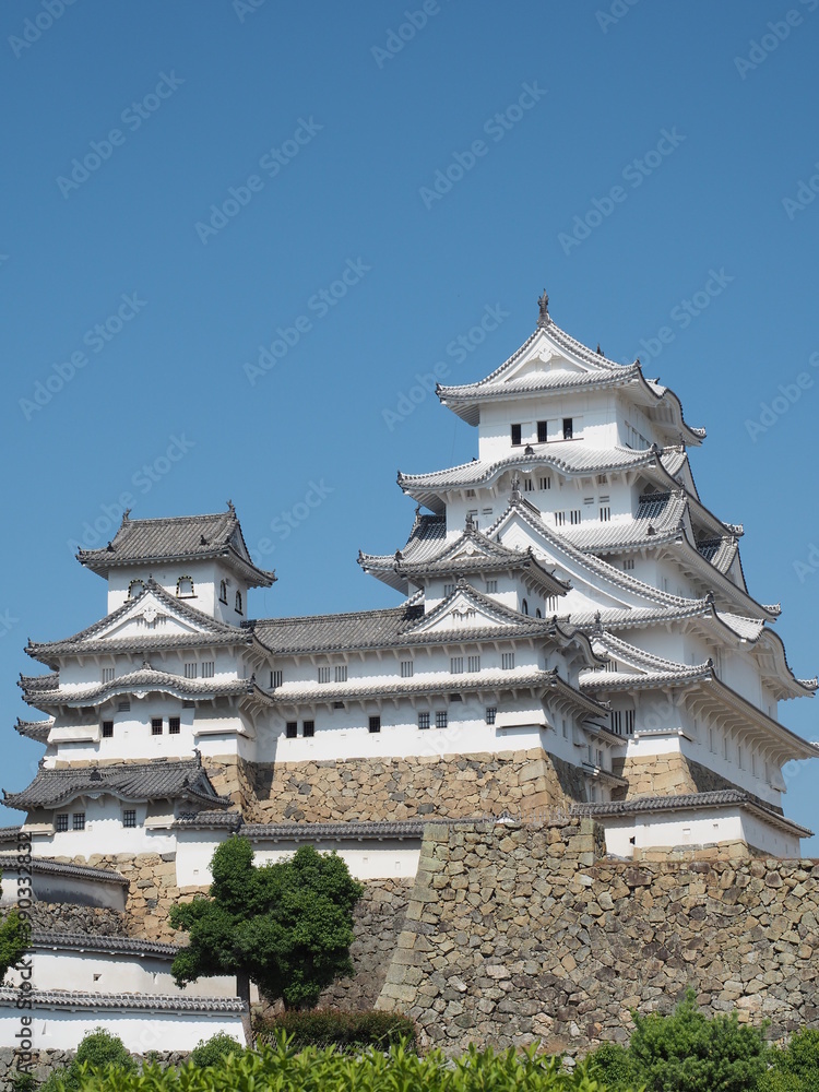 Ancient samurai castle in Himeji city in Japan with white walls, dark tile roofs and stone walls on a sunny day in summer with blue sky and white clouds Ancient samurai castle in Himeji city in Japan with white walls, dark tile roofs and stone walls on a sunny day in summer with blue sky and white clouds