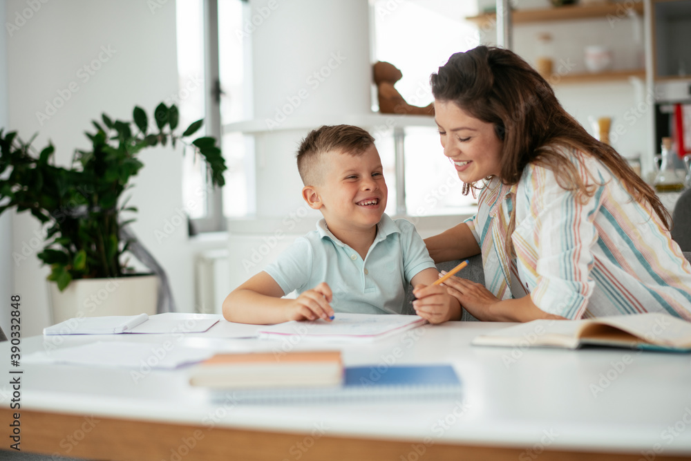 Mother helping her son with homework at home. Little boy learning at home.. Mother helping her son with homework at home. Little boy learning at home..