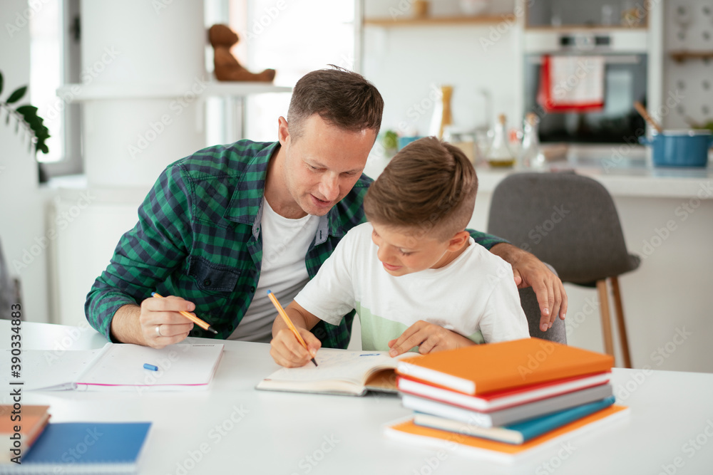 Father helping his son with homework at home. Little boy learning at home. Father helping his son with homework at home. Little boy learning at home.