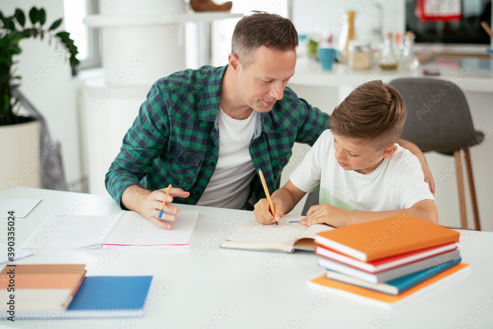 Father helping his son with homework at home. Little boy learning at home. Father helping his son with homework at home. Little boy learning at home.