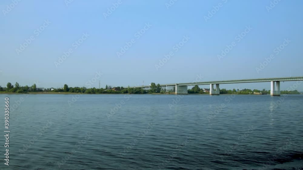 Automobile bridge over a wide river against the background of a blue sky. Traffic. Long shot. Automobile bridge over a wide river against the background of a blue sky. Traffic. Long shot.