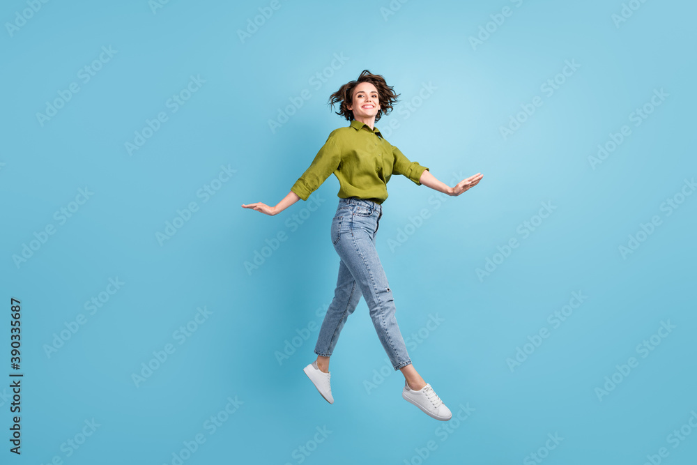 Photo portrait of graceful woman jumping up hands to sides isolated on pastel light blue colored background Photo portrait of graceful woman jumping up hands to sides isolated on pastel light blue colored background
