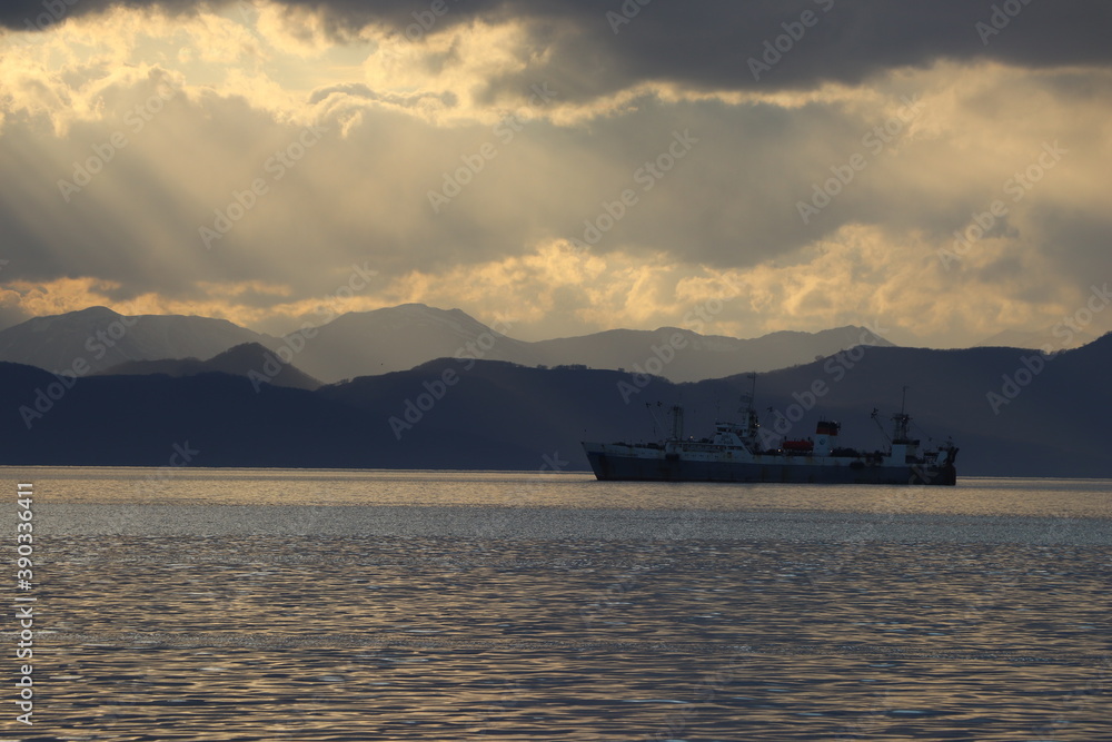 silhouette of an industrial ship against the background of mountains in the evening