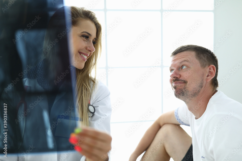 Obraz premium Doctor and patient are smiling at each other at doctor in the hands of an X-ray picture. Customer health insurance concept