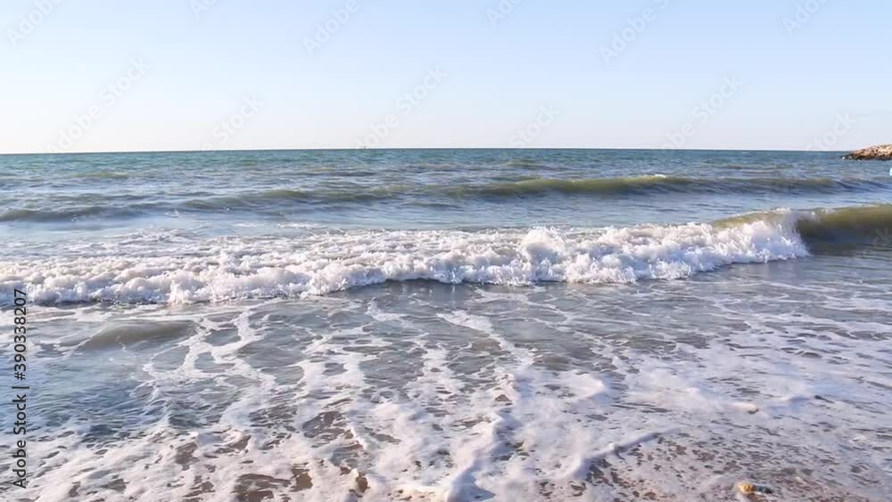 Sea waves crashing on a sandy beach and creating white water on a sunny summer. Sea waves crashing on a sandy beach and creating white water on a sunny summer.