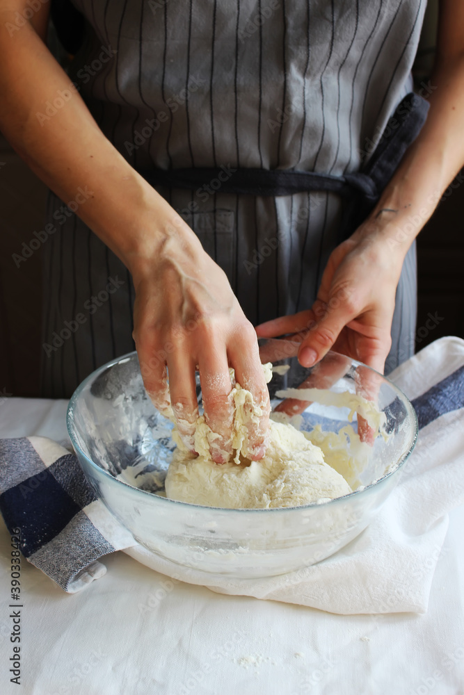 Household. Hands of a female housewife knead the dough in a large bowl. Family celebration.