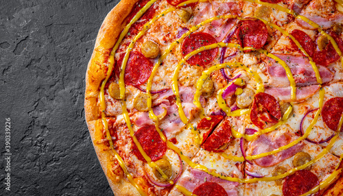 Pizza with Mozzarella cheese, ham, tomato sauce, pepper, pickled cucumbers and onion. Italian pizza on Dark grey black slate background