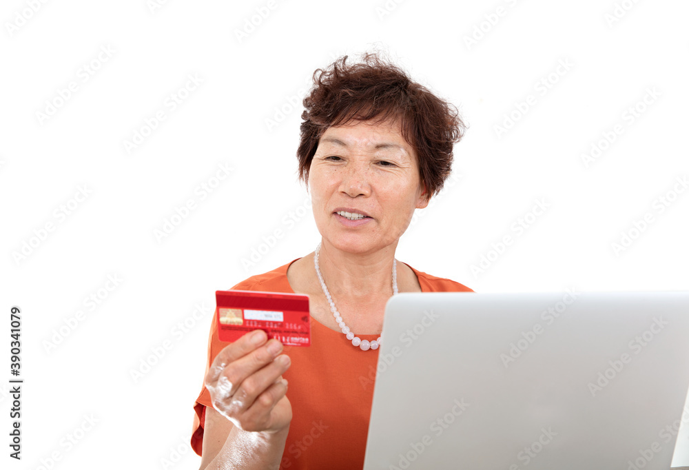 Chinese woman sitting in front of laptop smiling and looking at bank card in hand Chinese woman sitting in front of laptop smiling and looking at bank card in hand