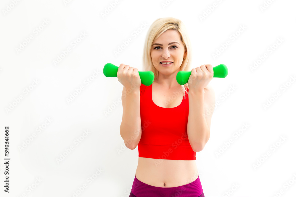 Smiling athletic woman pumping up muscles with dumbbells on white background Smiling athletic woman pumping up muscles with dumbbells on white background