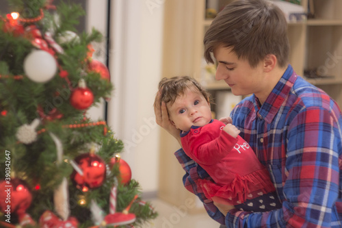 Loving father with an infant daughter near New Year tree