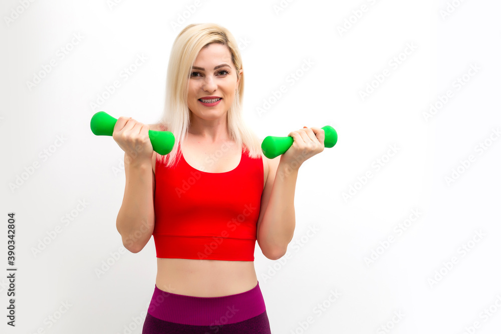 Smiling athletic woman pumping up muscles with dumbbells on white background Smiling athletic woman pumping up muscles with dumbbells on white background
