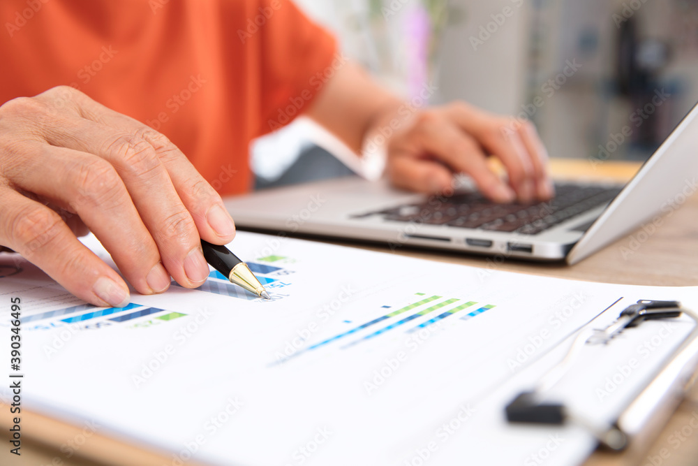 Female workers check financial data while operating laptops