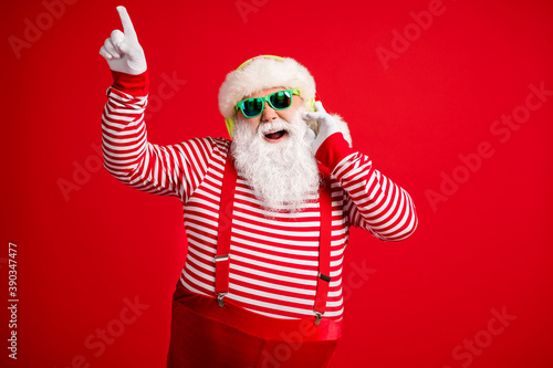 Portrait of his he handsome bearded fat overweight cheerful cheery Santa listening single hit sound having fun rest chill amusement leisure isolated bright vivid shine vibrant red color background © deagreez