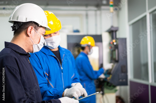 Asian engineer foreman discuss project on digital tablet with factory worker in industrial construction. industry people in face mask to prevent flu virus during company reopen. new normal working