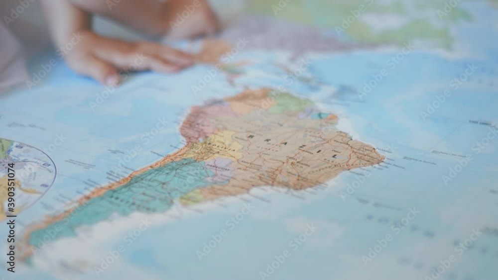 The hands of a little girl on a colorful map of South America pointing at Brazil The hands of a little girl on a colorful map of South America pointing at Brazil