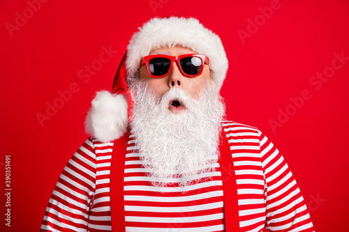 Close-up portrait of his he nice handsome attractive amazed stunned white-haired Santa christmastime sale wearing sunglasses isolated over bright vivid shine vibrant red color background © deagreez