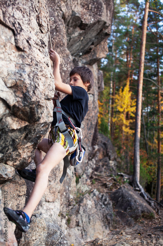 cute teen kid climbing on rock with insurance, lifestyle sport people concept