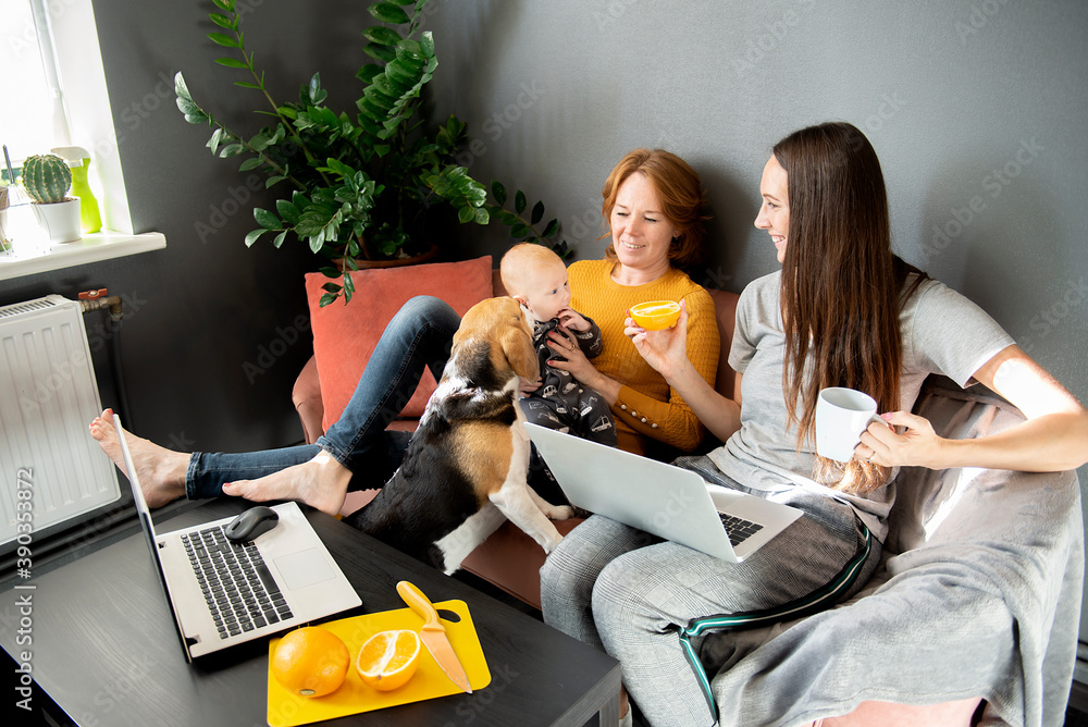 Naklejka premium happy family - grandmother, daughter, newborn baby and dog rest in the living room on the couch