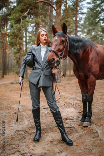 Girl rider standing next to the horse. The girl holds the horse's bridle © Alexey Tsibin
