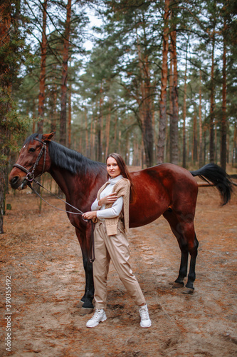 Girl rider standing next to the horse. The girl holds the horse's bridle © Alexey Tsibin