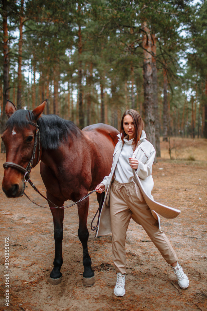 Girl rider standing next to the horse. The girl holds the horse's bridle Girl rider standing next to the horse. The girl holds the horse's bridle