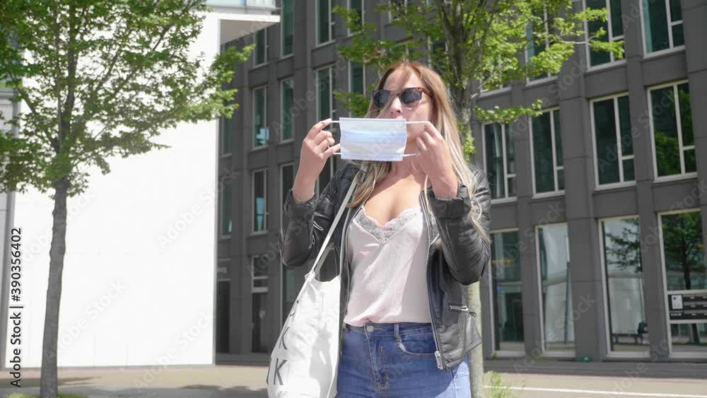 Pretty Blond Woman With Dark Sunglasses Put On Facemask In Amsterdam, Netherlands. - Coronavirus Pandemic - Medium Shot - Slow Motion Pretty Blond Woman With Dark Sunglasses Put On Facemask In Amsterdam, Netherlands. - Coronavirus Pandemic - Medium Shot - Slow Motion