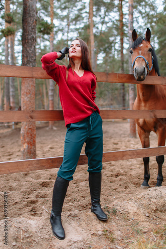 A girl standing next to a horse. Demonstration of clothing by a model