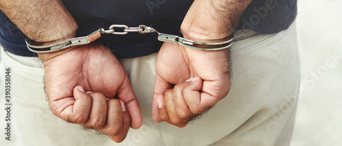Prisoner male criminal standing in handcuffs with hands behind back. banner copy space. 