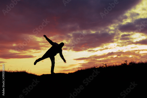 silhouette of a man standing on one leg and balancing trying to maintain balance
