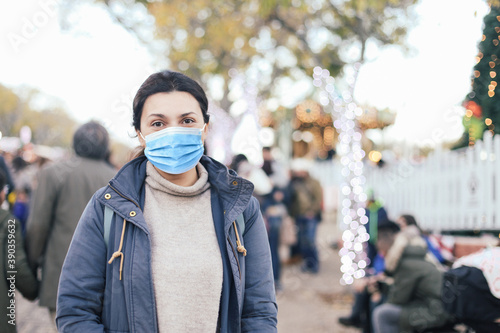 Young woman in blue medical mask on a Christmas market smiling photo