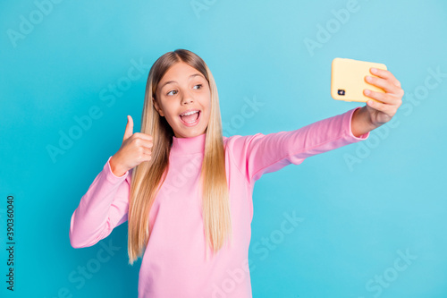 Photo portrait of pretty female preteen taking selfie showing thumb-up gesture like isolated on bright teal color background © deagreez