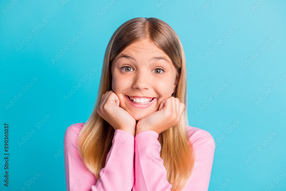 Fototapeta premium Photo portrait of cute schoolgirl with blonde hair smiling cheerfully keeping hands near face isolated on vivid turquoise color background