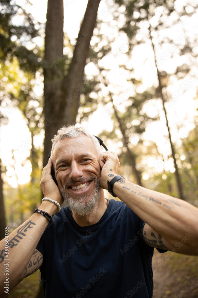 Joyful man in earphones running in forest Joyful man in earphones running in forest